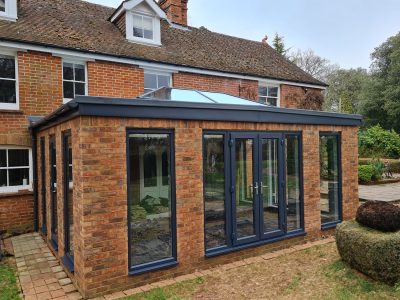 Large Orangery with anthracite tall windows, lantern roof and French doors build by contractor River ODP in West Sussex