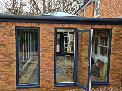 Side view of Large Orangery with anthracite tall windows and French doors build by contractor River ODP in West Sussex