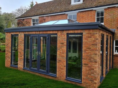 Solid construction Orangery with anthracite tall windows, lantern roof and French doors build by contractor River ODP in West Sussex